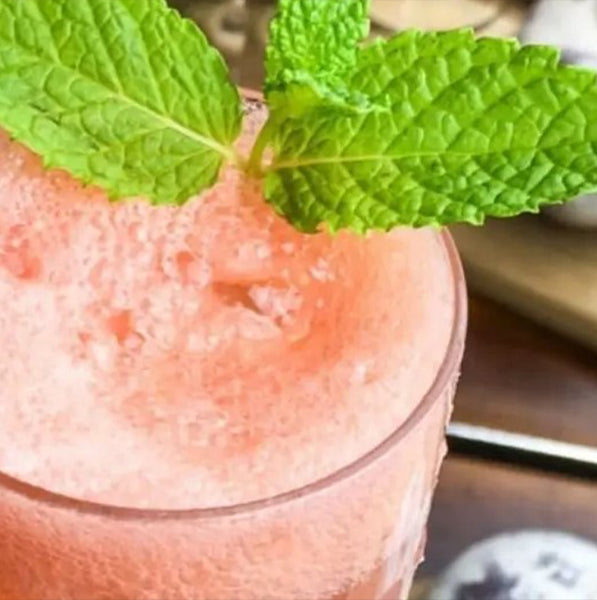 Close up of a mint grapefruit mimosa cocktail with fresh mint garnish with a link to the recipe