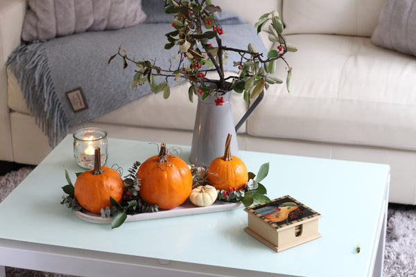 coffee table with pumpkins, vase and stems