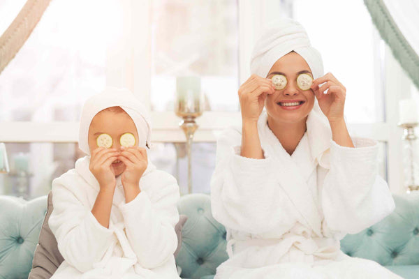 Mother and daughter in a spa setting wearing robes and cucumbers on their eyes
