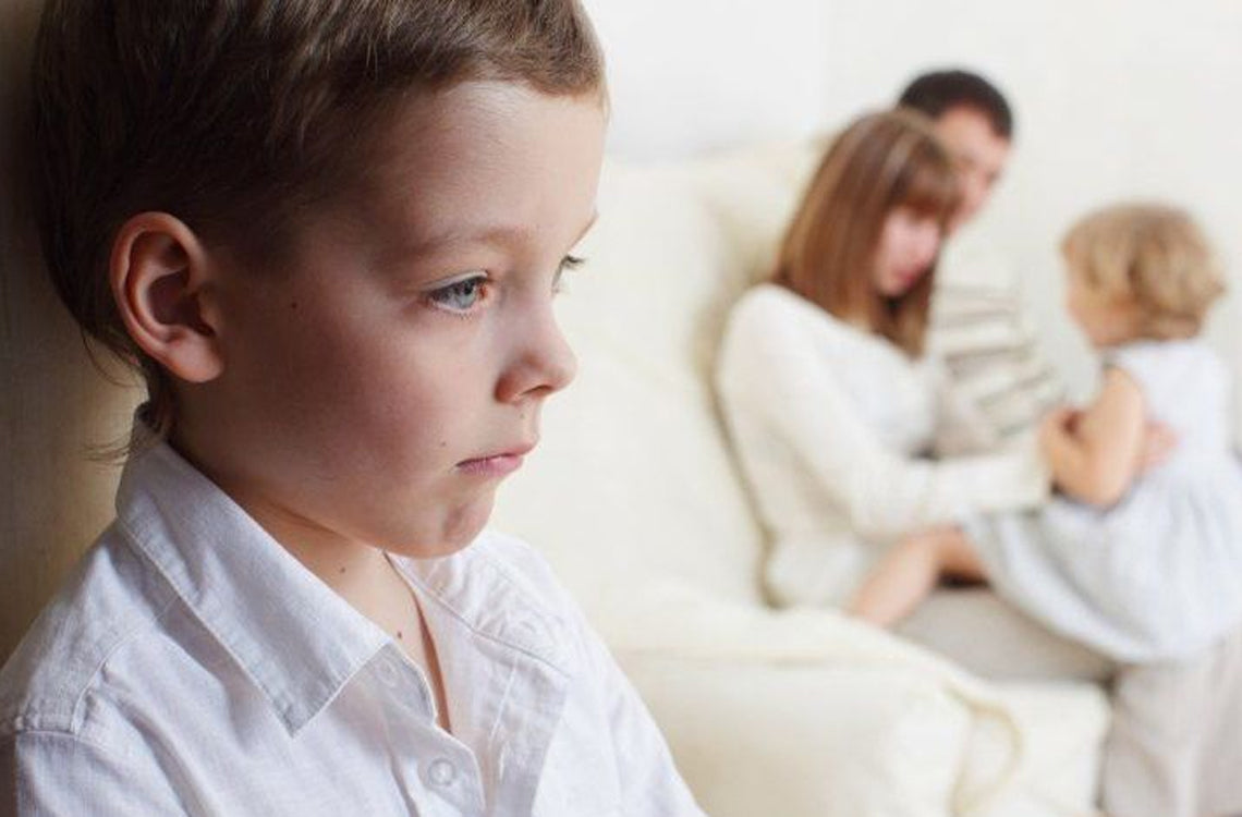 sad little boy with his family in the background