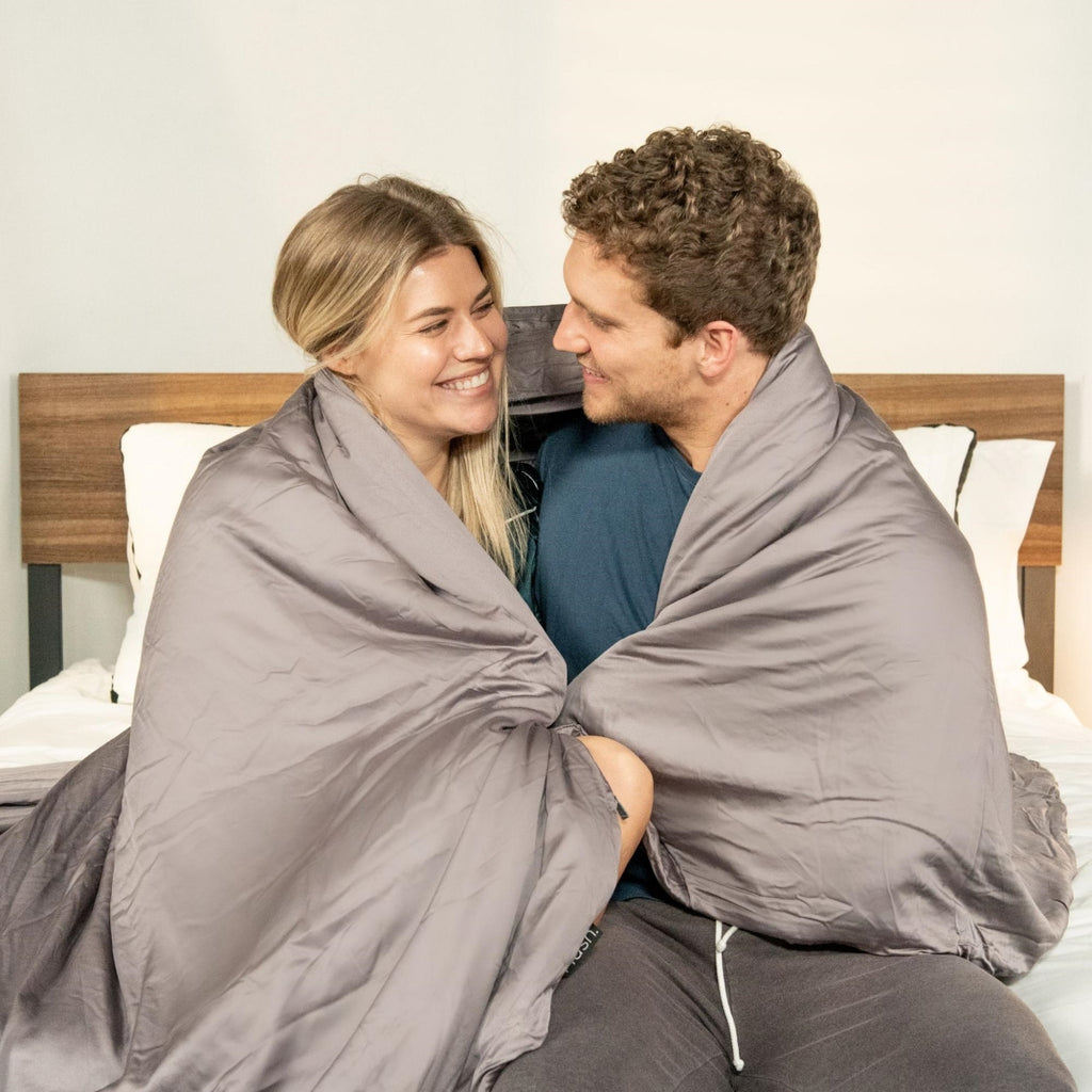 Smiling couple looking at each other with a blanket over their shoulders