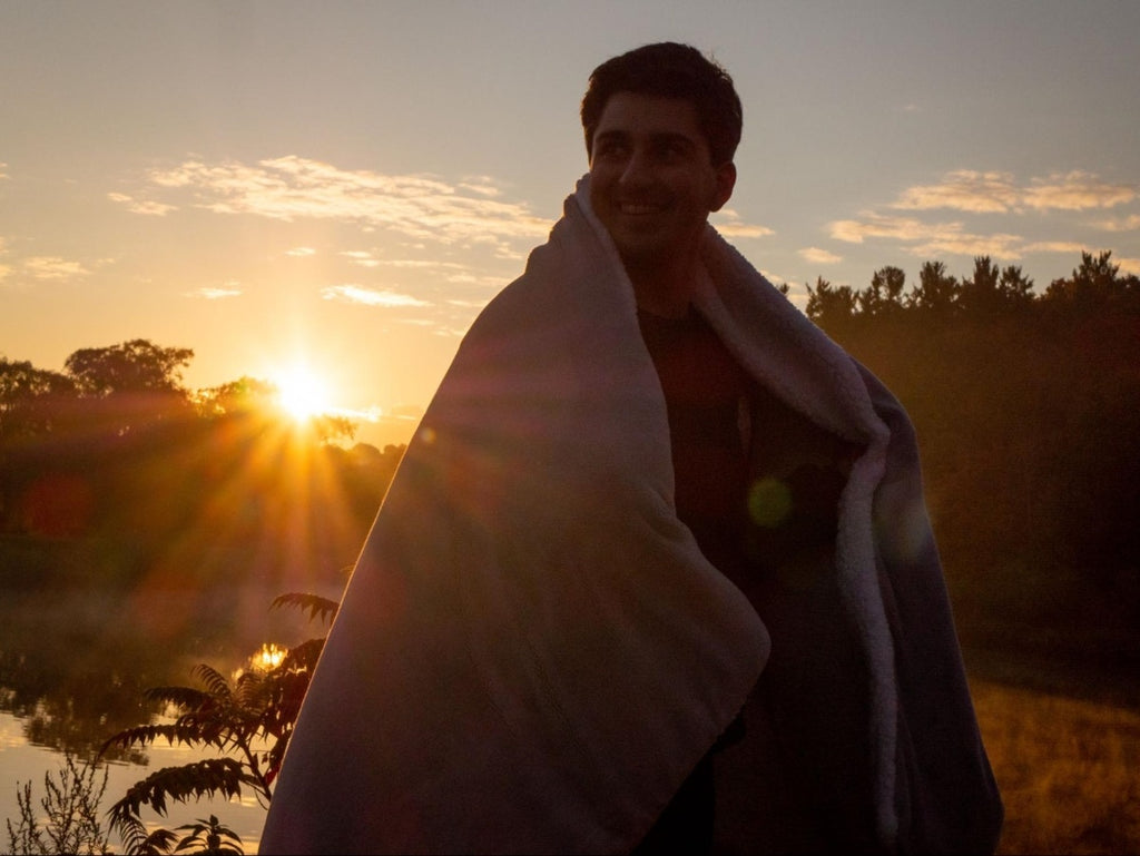 Smiling man with a blanket wrapped around his shoulders while outdoors