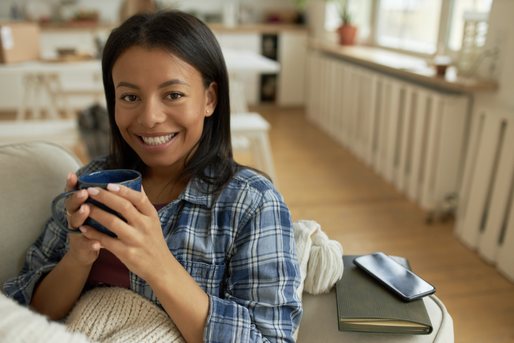 gifts for people with anxiety: Smiling woman looking at the camera while holding a mug