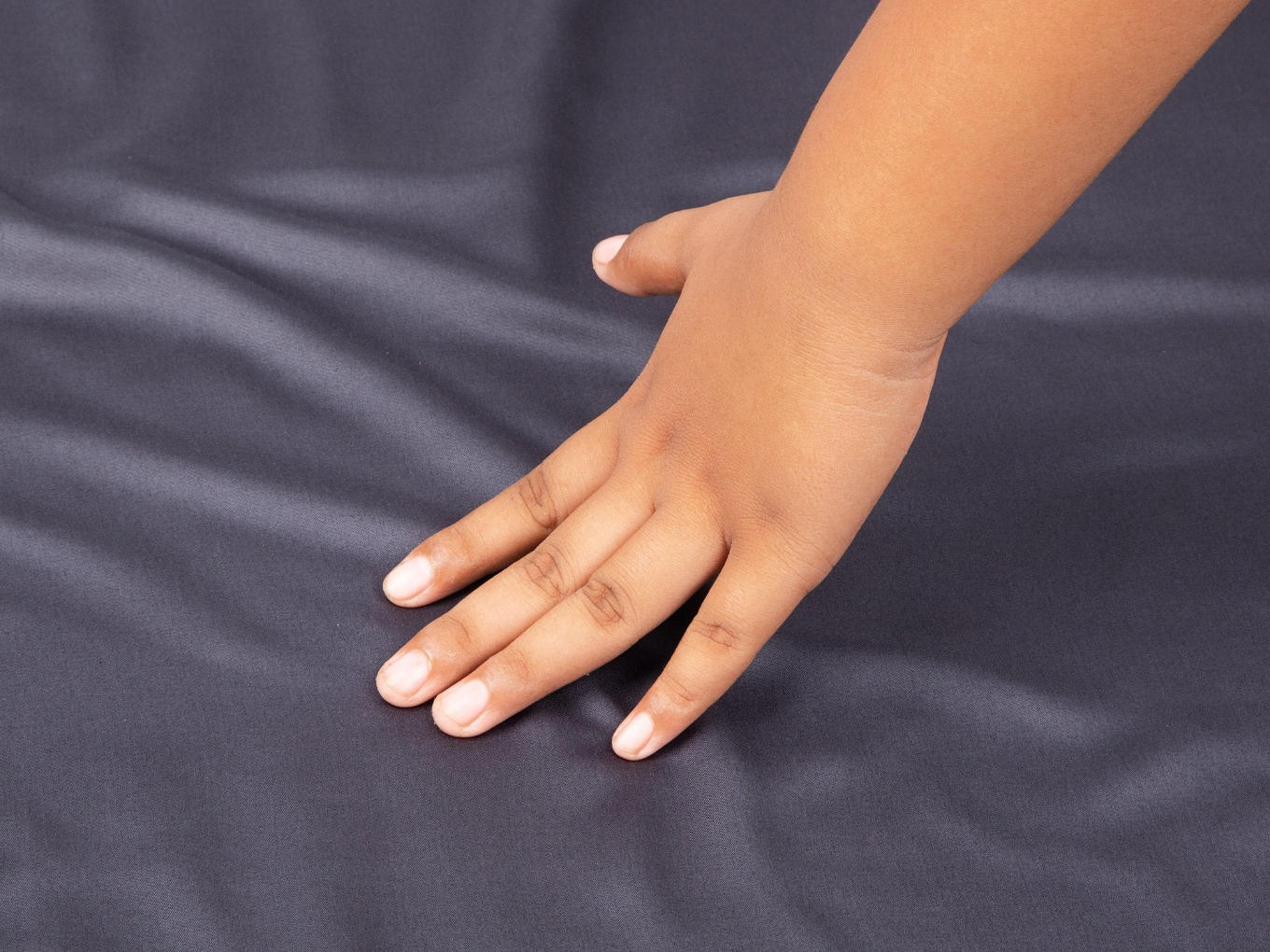 A person touching the Hush Iced Bamboo Cooling Sheet in charcoal color.