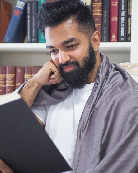 how to use a weighted blanket: man reading with a blanket over his shoulders