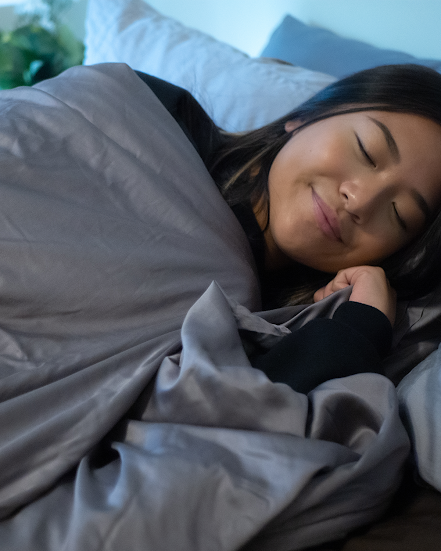 how to use a weighted blanket: woman sleeping with a blanket on