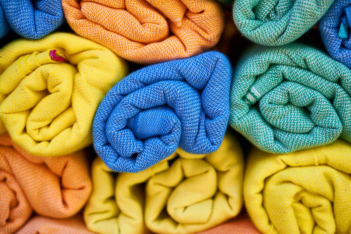 Several towels in different colors rolled and piled together.