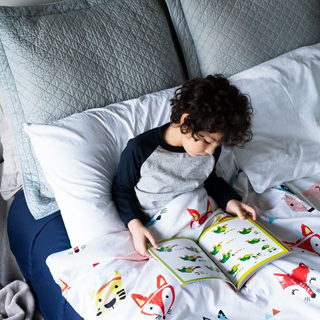 little boy reading a book under Hush weighted blanket for sensory issues