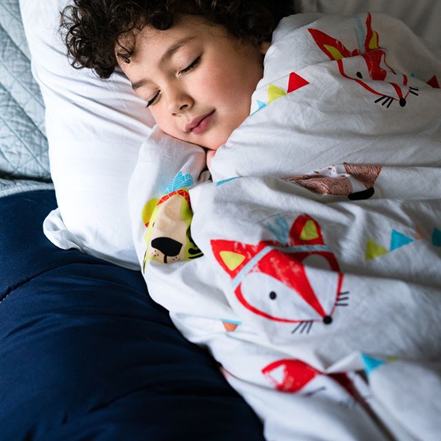 little boy sleeping peacefully wrapped in Hush weighted blanket for sensory issues