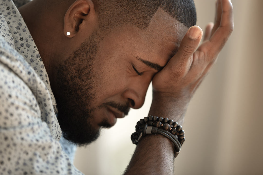 sensory overload anxiety: man with a headache pressing his forehead