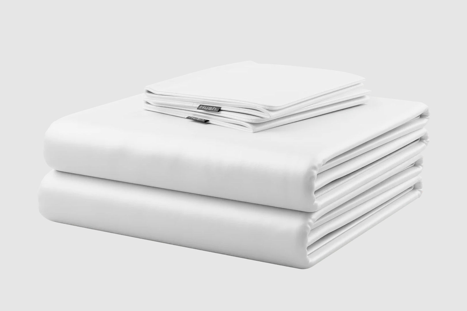 A set of white Hush cooling sheets and pillowcases neatly folded on a white background.