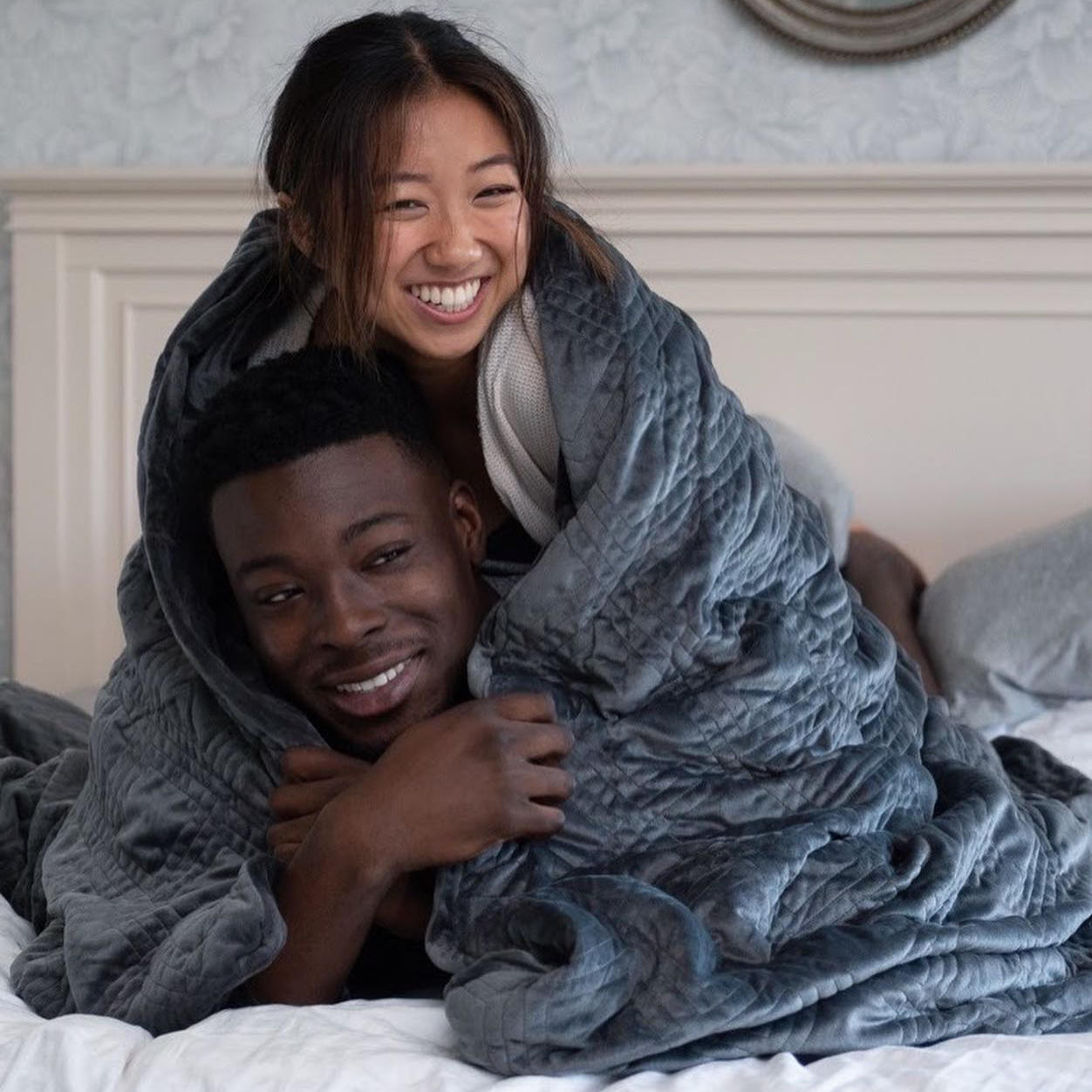 A couple happily sharing a Hush Classic Weighted Blanket.
