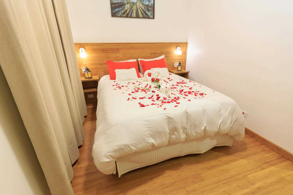 a bed covered with white duvet and rose petals