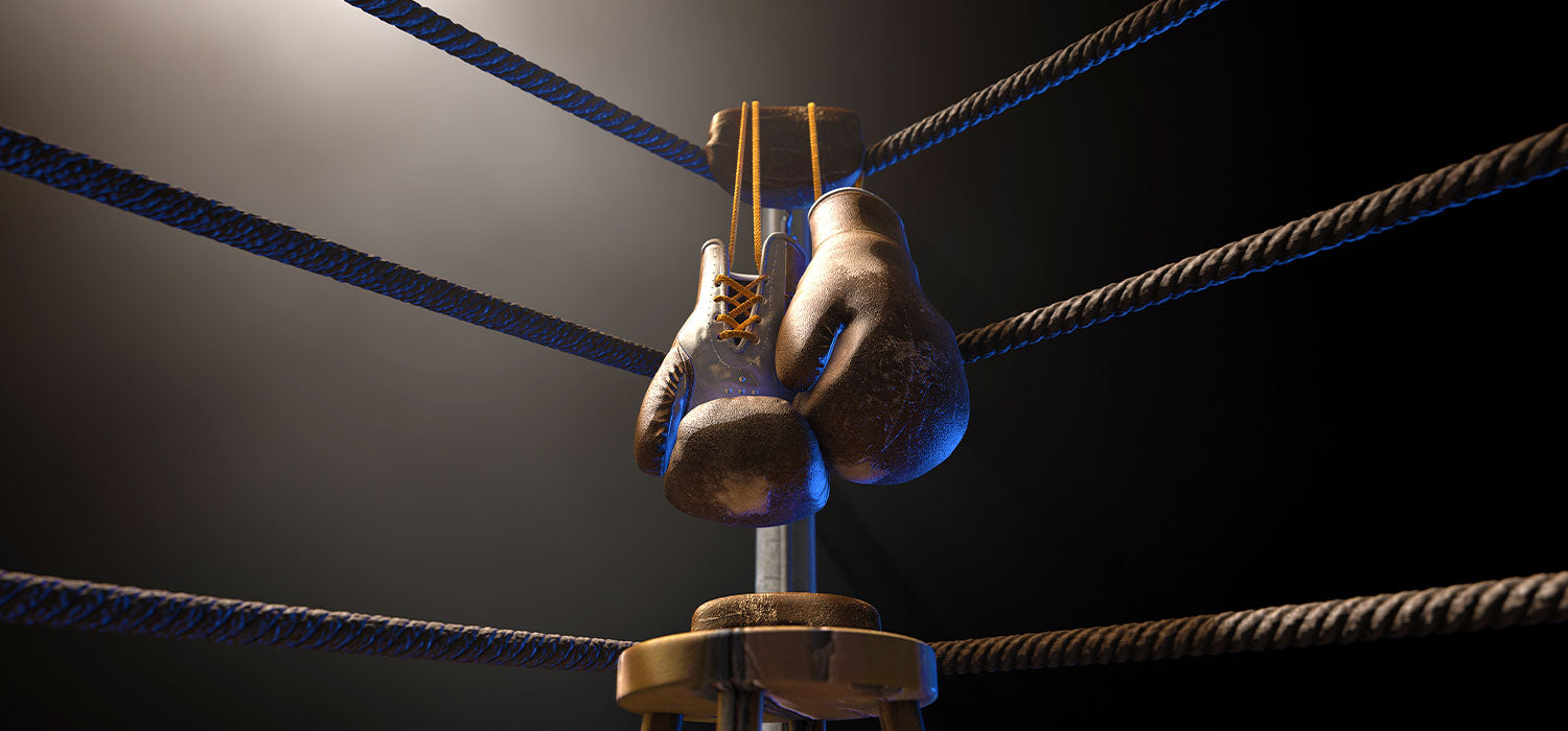 Pair of boxing gloves tied to the ropes in the corner of a boxing ring