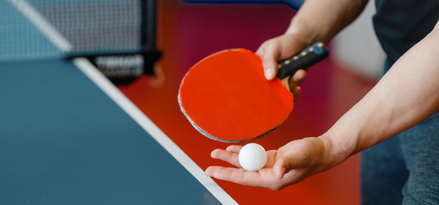 Man holding a table tennis ball and bat about to play table tennis