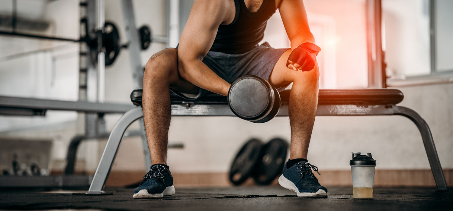 Man sitting on a weight bench lifting dumbbells