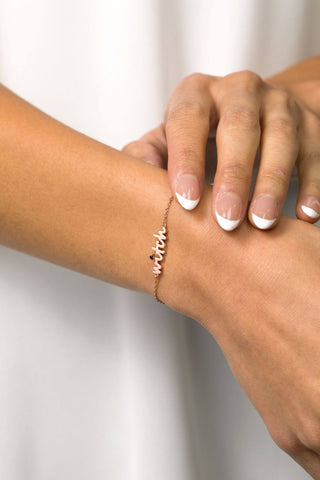 Elegant bracelet with the word Witch in cursive script worn on model's hand
