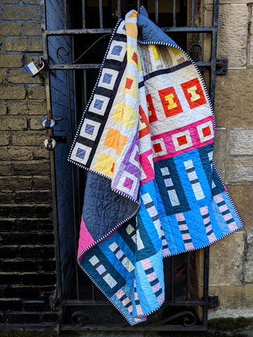 Go Quilt by lucy engels sew along quilt, brightly coloured quilt hanging on a gate 