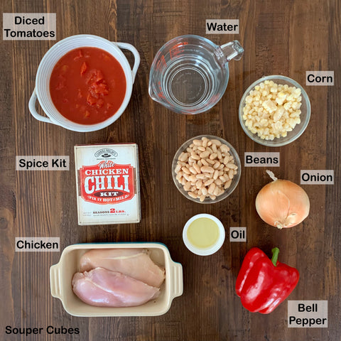 overview of ingredients for chicken chili in various bowls on a wooden table