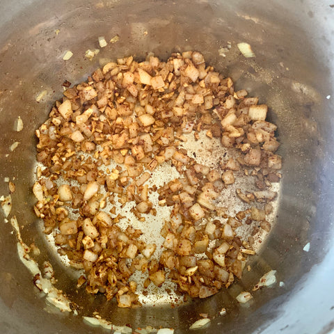 Onions and garlic stirred with spices in Instant Pot