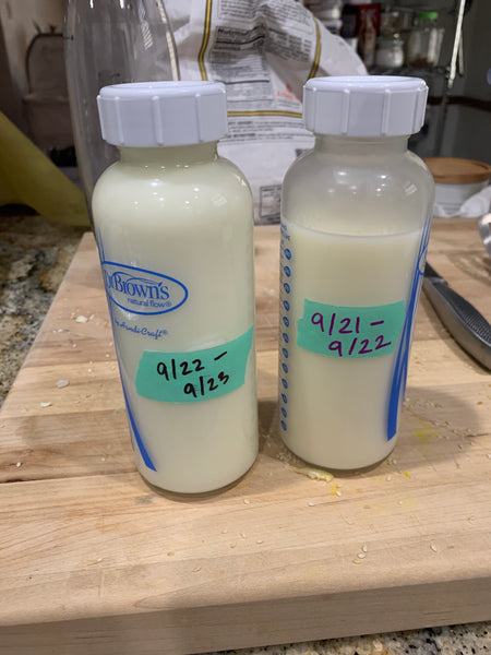 image of two glass bottles filled with breast milk, labeled with dates