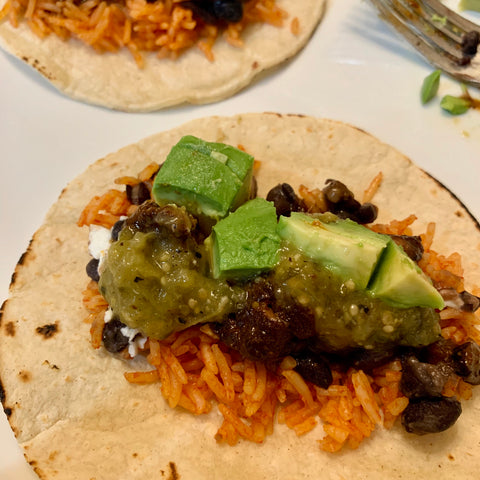 salsa verde on an open beef taco with avocado, rice, and black beans