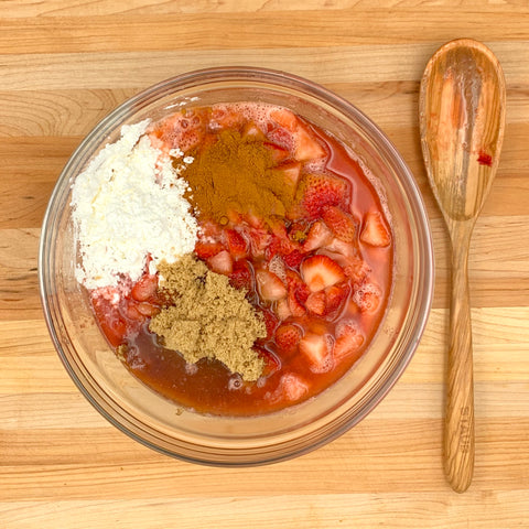 bowl with reduced strawberries, reduced rhubarb, brown and granulated sugar, cinnamon, and corn starch for strawberry rhubarb crisp recipe