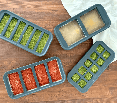 Four different sized Souper Cubes® trays laid out on the counter with different meals prepared in each one. 