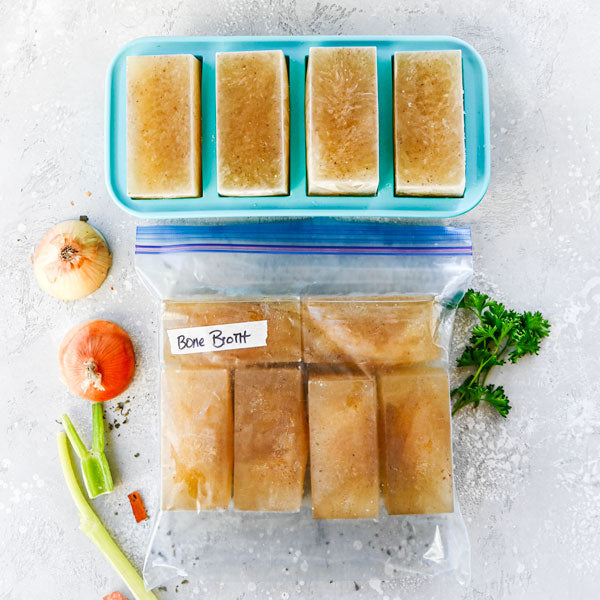 overhead image of bone broth frozen in 1-cup souper cubes trays with some cubes placed in a ziploc bag