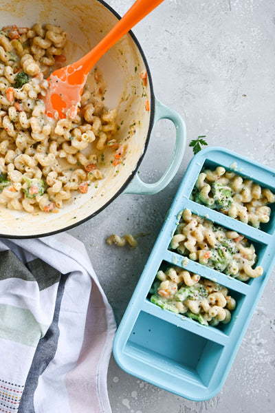 veggie Mac and cheese in 1-cup souper cubes tray next to a pot with more veggie mac and cheese