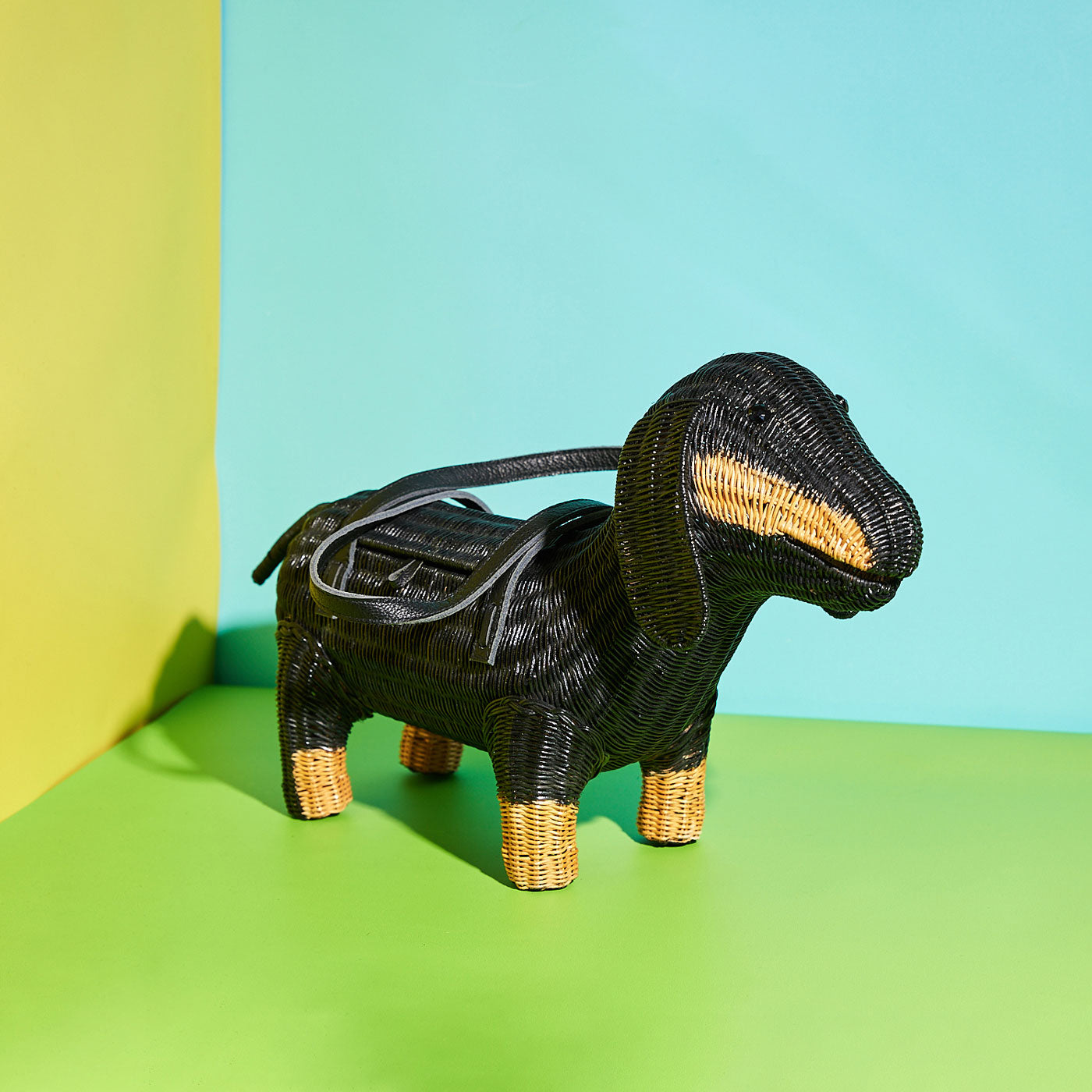 Frank the Black Wicker Darling sausage dog purse standing on a green background