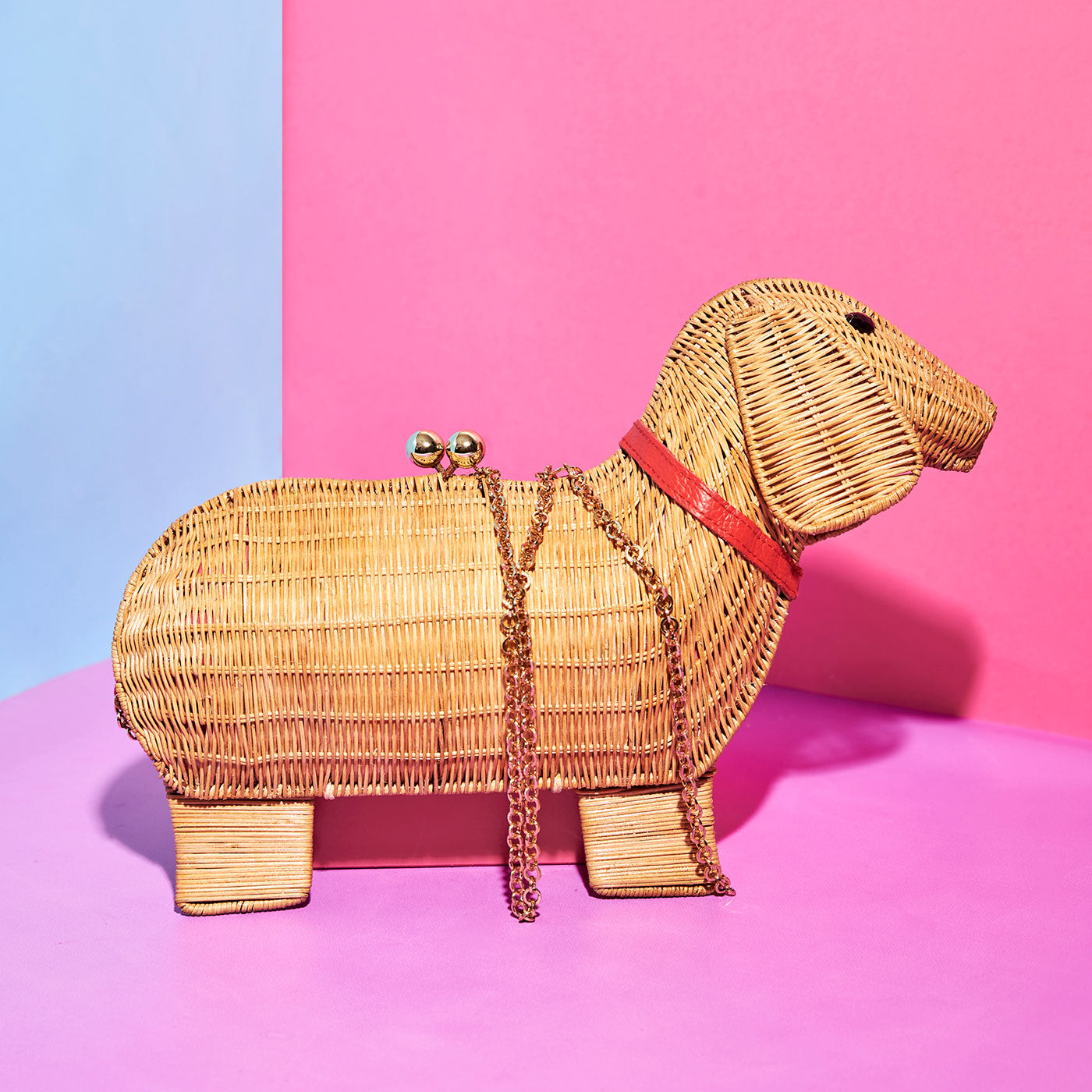 Mash the sausage dog Wicker Darling clutch on a pink, blue background