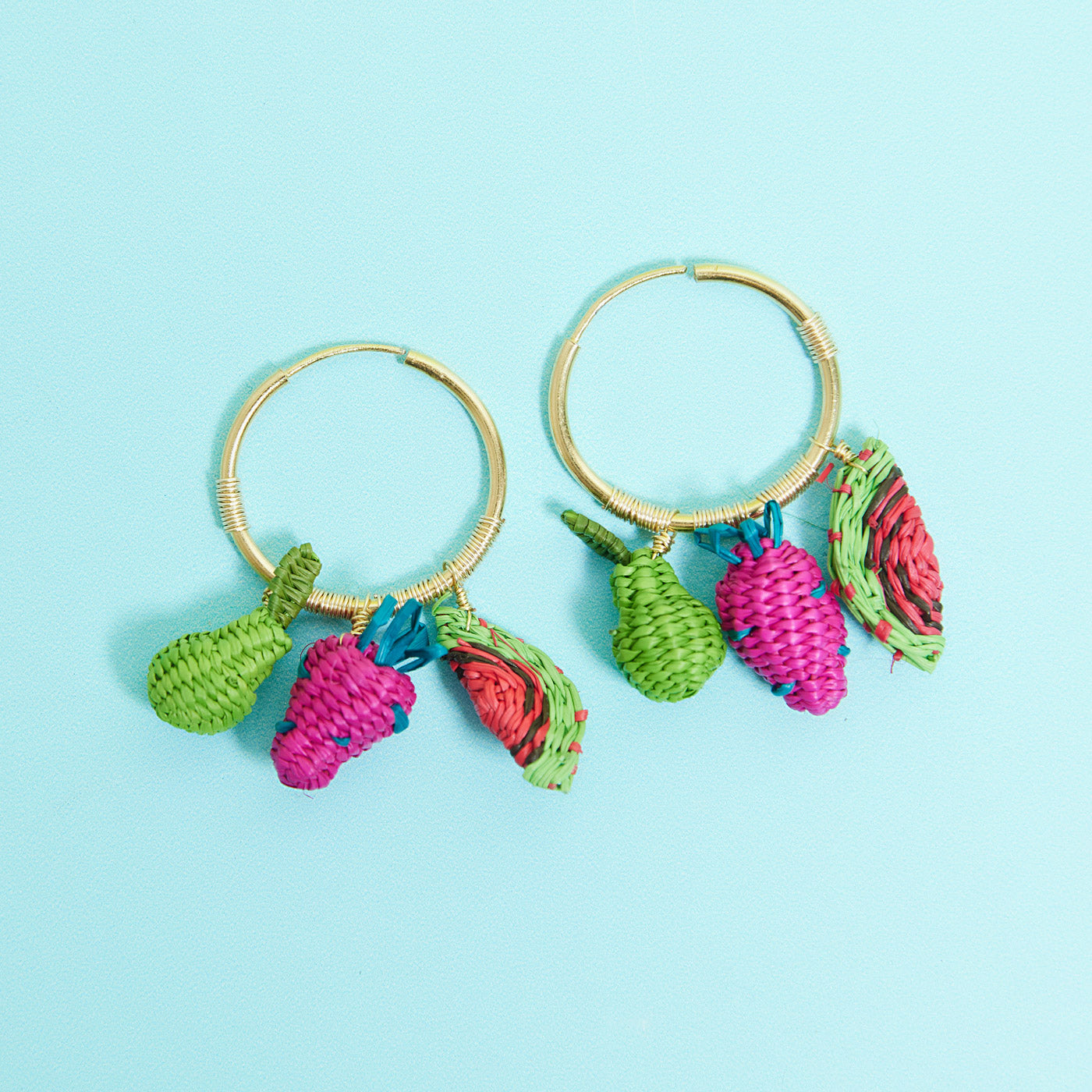Fruit salad earrings from Wicker Darling on a blue background