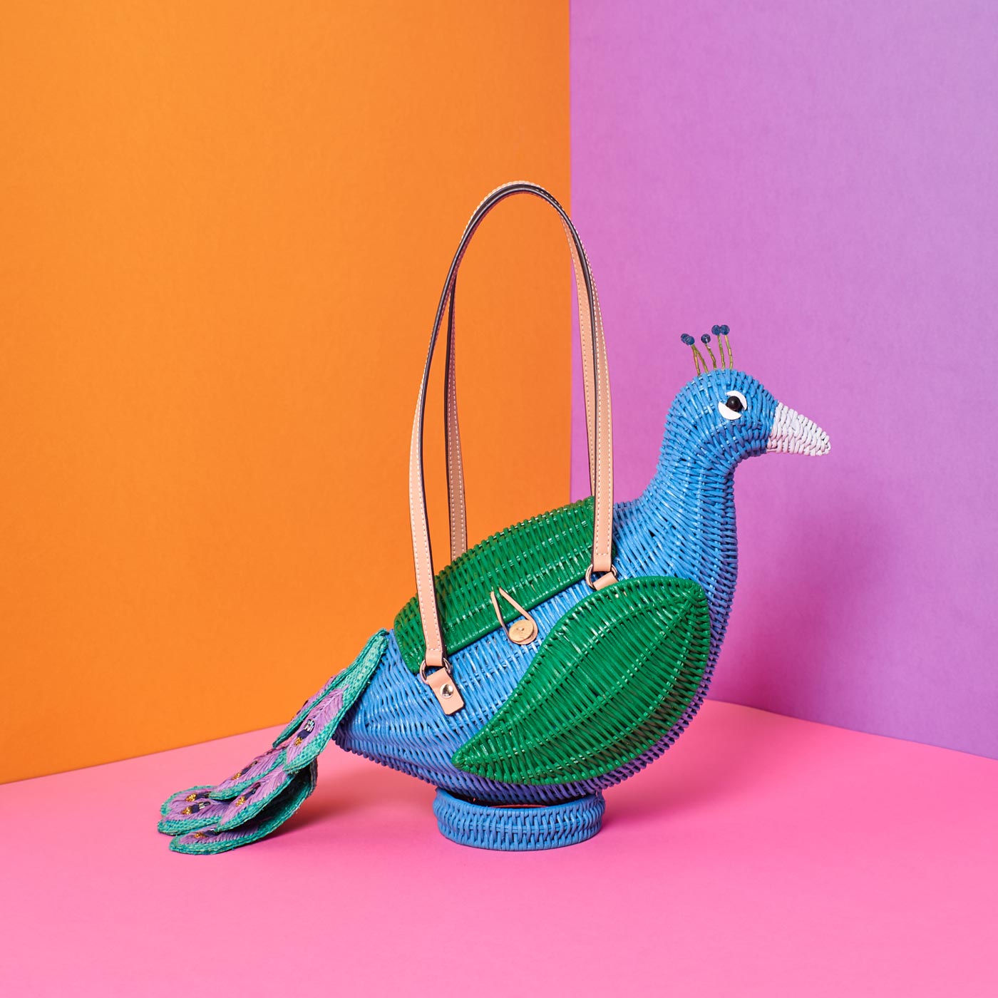 Wicker Darling percy peacock tail purse wicker bag sits in a colourful background