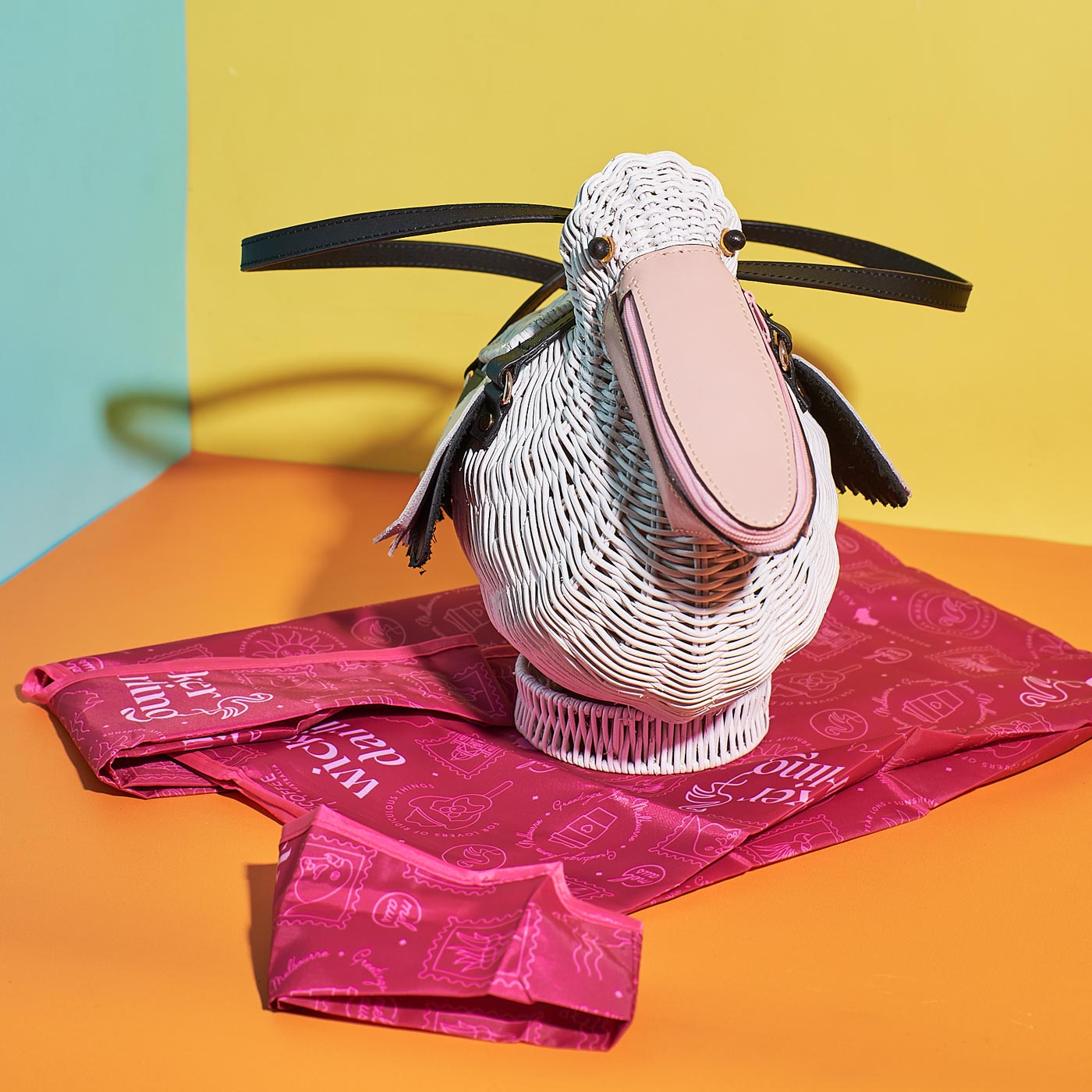 Pelican Bill the Wicker Pelican Bag sitting on Wicker Darling's pink fabric dust bag/shopping totes 
