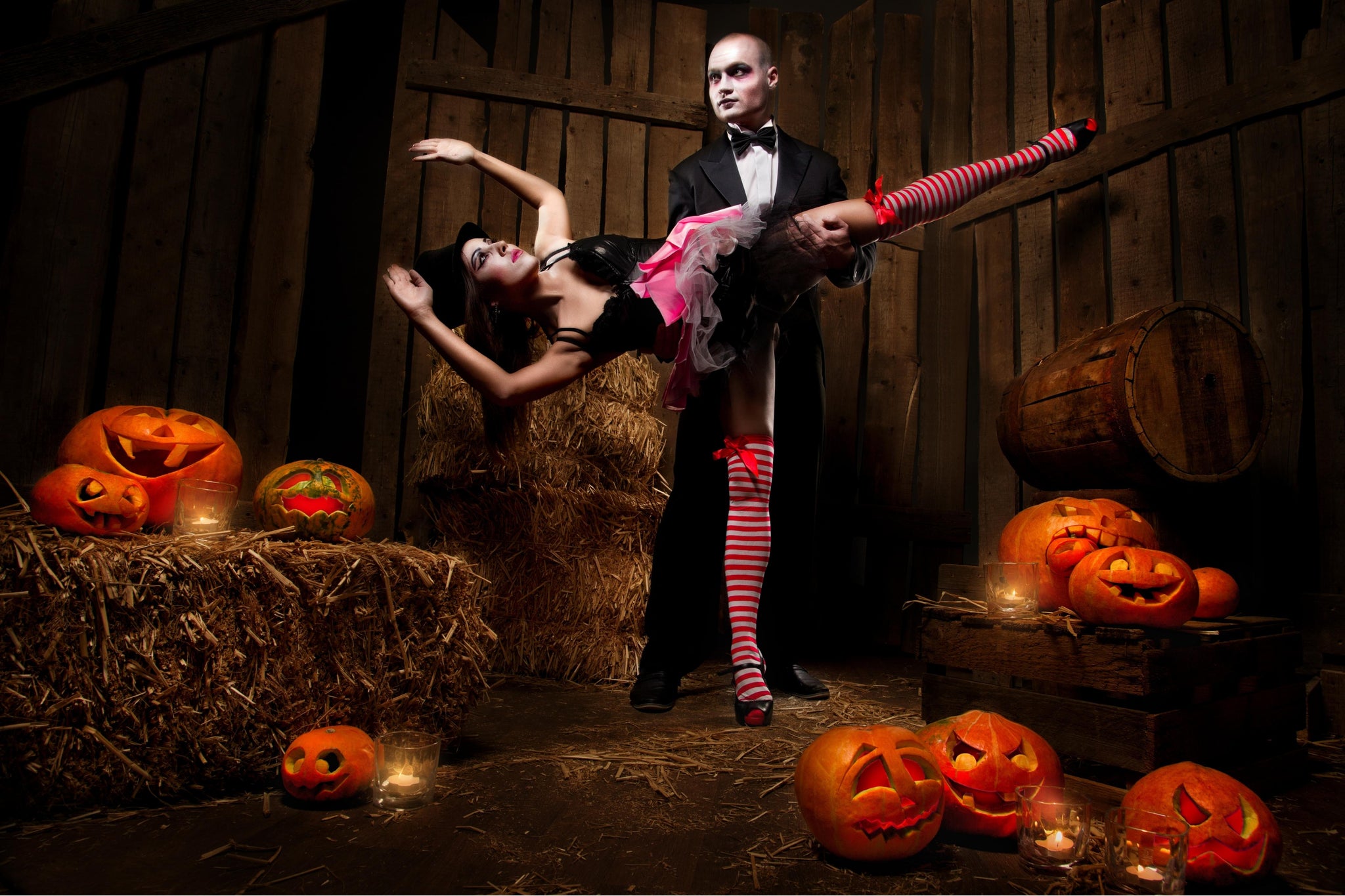 A Halloween couple dancing in a haunted Halloween barn with lots of pumpkins