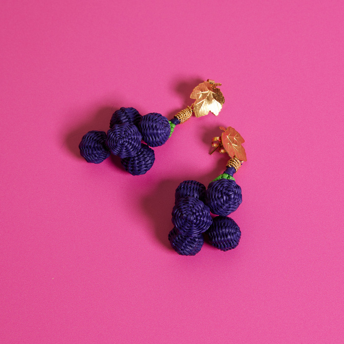 Wicker Darling's Grape earrings on a pink background