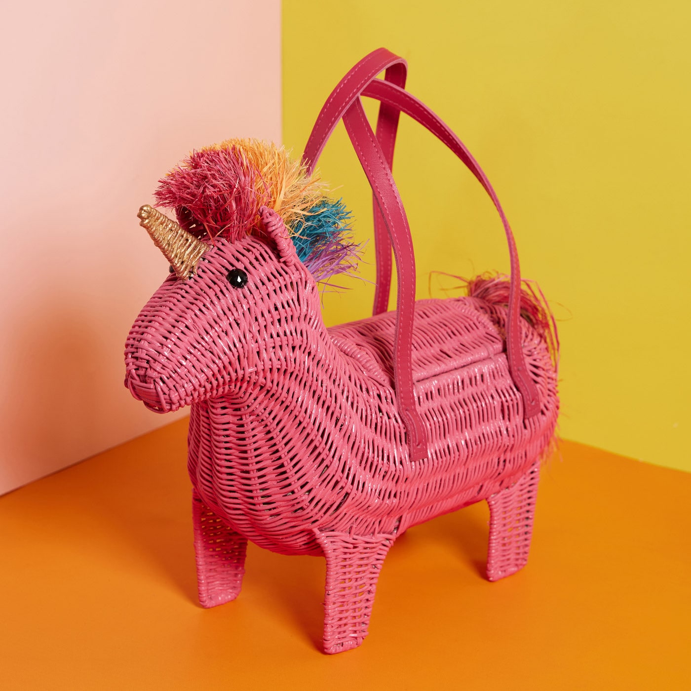 Wicker Darling's Viola the pink unicorn purse on a colourful background