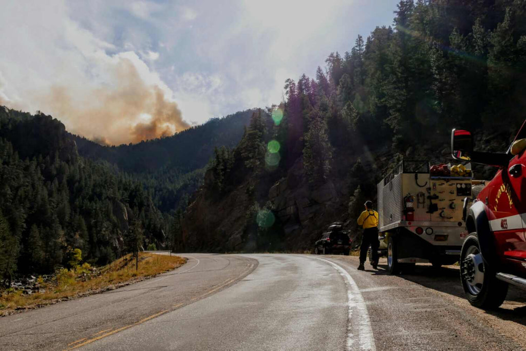 fire truck on roadside with wildfire smoke in distance