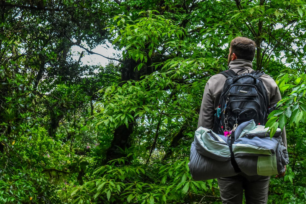 man carrying backpack in the woods