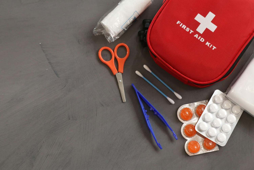 scissors, tweezers, cotton swabs and first aid kit bag on gray background