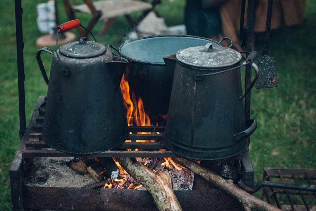three pots on top of campfire