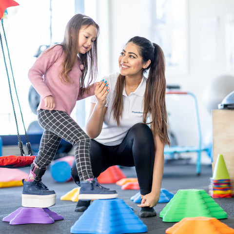 kid doing an indoor obstacle course with the help of an adult