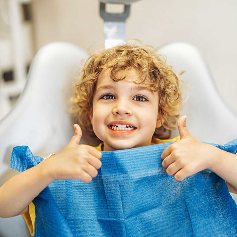 kid giving thumbs up in dentist chair