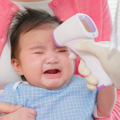 baby crying and getting temperature taken on forehead