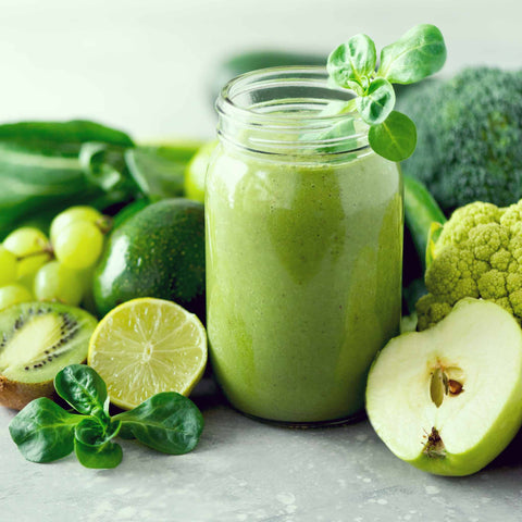 green smoothie surrounded by green fruits and vegetables