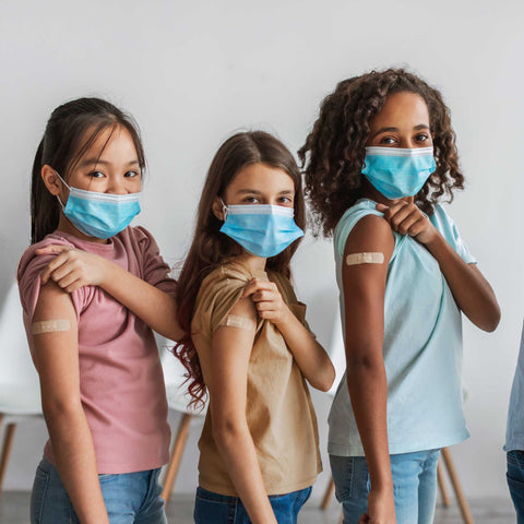 kids wearing masks and showing their band-aids after doctor's visit