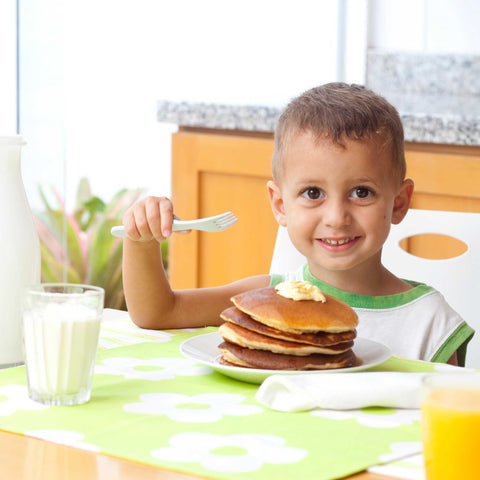 kid smiling and eating pancakes