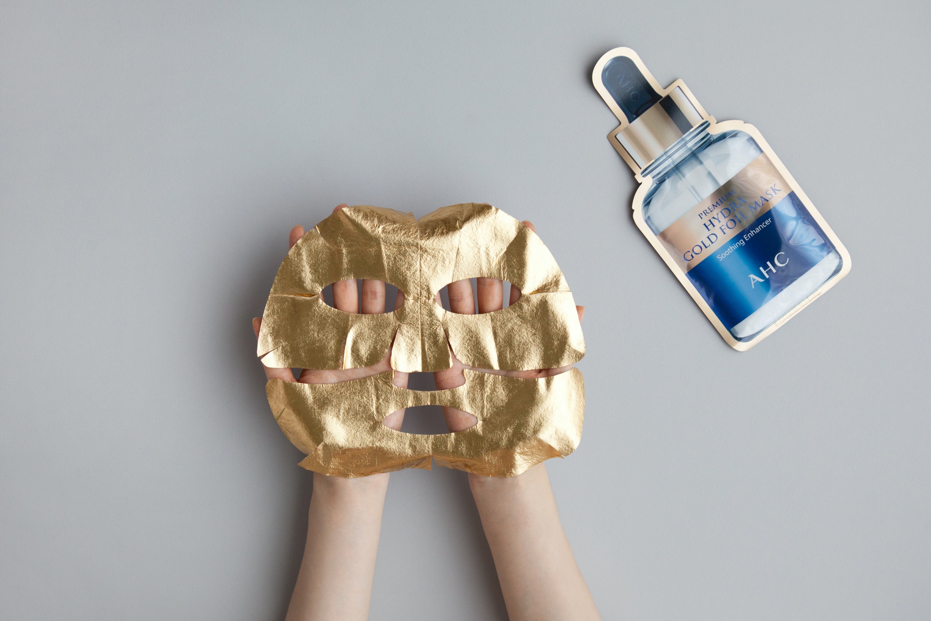 A hand holding AHC Premium Hydra Gold Foil Mask