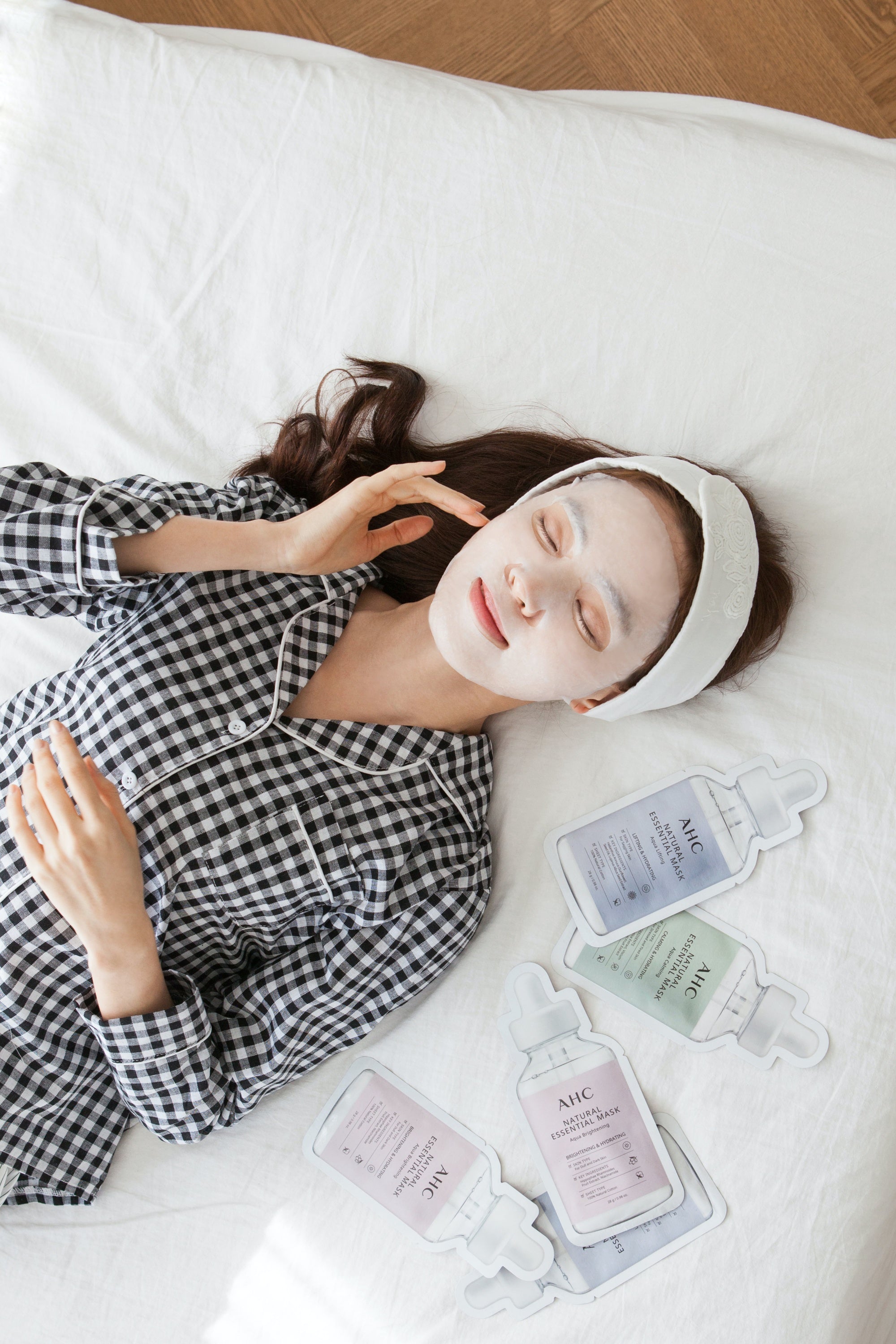 Asian woman in bed using AHC Essential Sheet Mask